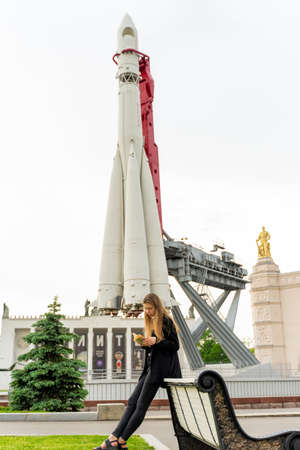 Moscow, Russia- MAY 23, 2019: Moscow, Russia- MAY 23, 2019: A girl reads a book in front of the Model of the Vostok Rocket, which was launched with Yuri Gagarin on board on April 12,1961, the first human who flew into outer space. Exhibited. In the VDNKh のeditorial素材