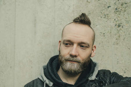 thinking bearded man looking down in front of a wall