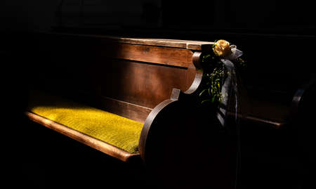 a church bench decorated with a rose for a wedding