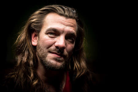 Man with long hair looks seriously at the camera
