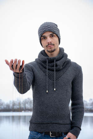 A man runs a viscous juice through his fingers. He looks questioningly and seriously at the camera.