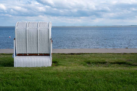 A beach chair in a meadow by the sea. The neighboring beach chair was removed as part of the Covid-19 prevention.の写真素材