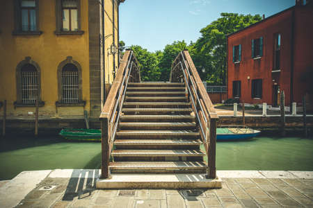 a wooden bridge over a canal in venice, italyの写真素材