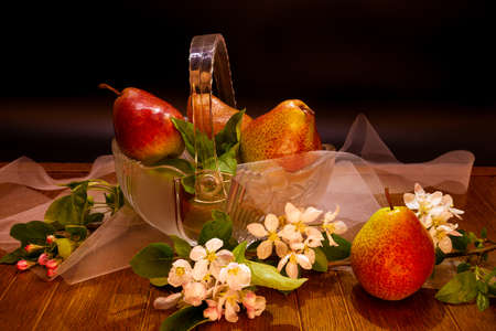 Fresh pears with pear blossoms on a dramatic dark wood background. Naturmort made from pears in a glass bowl.の写真素材