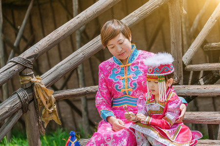 Mongolian mother and daughter sitting on wooden stepsの写真素材