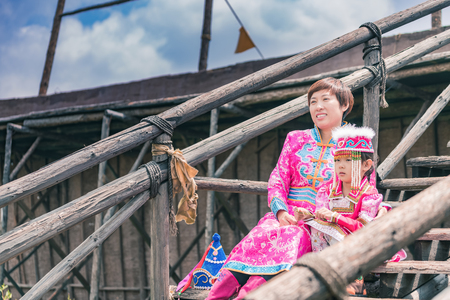 Mongolian mother and daughter sitting on wooden stepsの写真素材