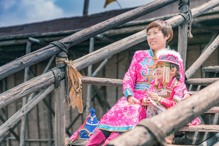 Mongolian mother and daughter sitting on wooden stepsの写真素材