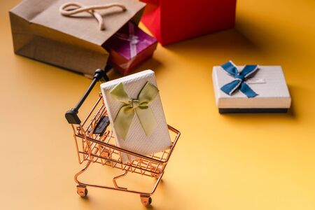 Shopping cart and gift boxes on yellow backgroundの写真素材