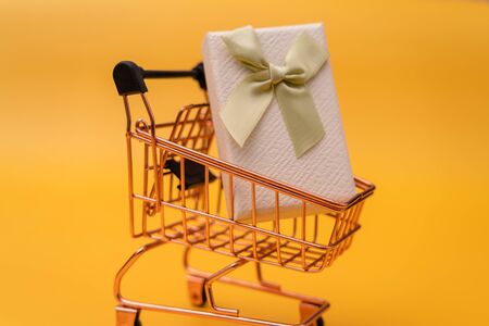 Shopping cart and gift box on yellow backgroundの写真素材