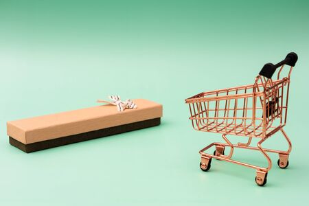 Gift box and shopping cart on green backgroundの写真素材