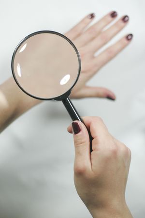 Looking at skin with magnifying glassの写真素材