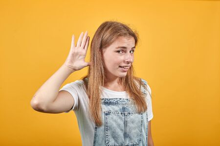 Young woman wearing white t-shirt, over orange background shows emotions