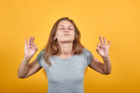 brunette girl in gray t-shirt over isolated orange background shows emotionsの写真素材