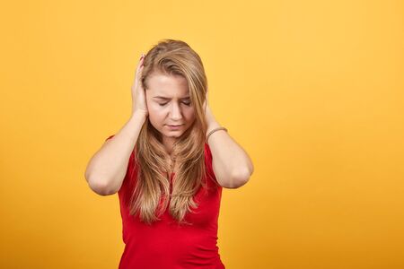 young blonde girl in red t-shirt over isolated orange background shows emotionsの写真素材