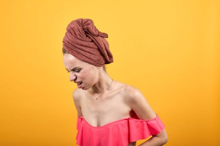 young girl with towel on her head over isolated orange background shows emotionsの写真素材