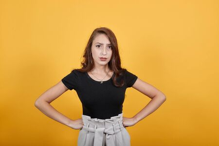 Cute girl standing in front of orange background not happy for sure. She is in shock as someone did something she never expected which has risen many questions in her mind.の写真素材