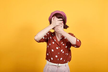 Young pretty caucasian woman wearing red shirt with white polka dot over isolated yellow background...