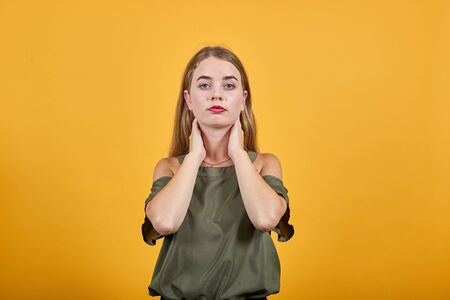 Close up brunette isolated on beige orange wall background, studio portrait, keeping hand on neck...