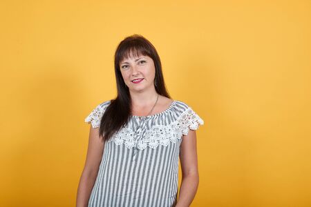 LVIV, UKRAINE - SEPT 06, 2019: Woman smiling as she is happy. She is posing to capture a photograph standing near the orange background and wearing gray and white striped shirt which looks elegant.のeditorial素材