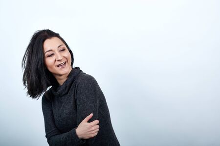 Beautiful caucasian young woman in fashion black sweater over isolated white background, crossed...
