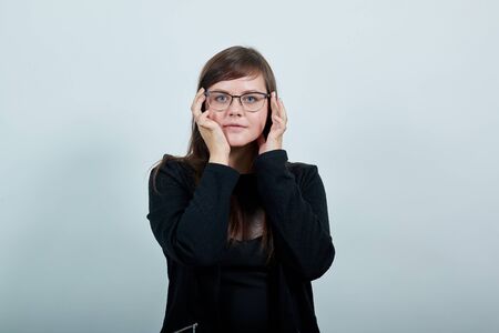 Young beautiful caucasian woman keeping hand on face, model gesture wearing casual black dress on...
