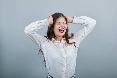 Charming caucasian young woman in fashion white shirt isolated on gray background in studio holding...