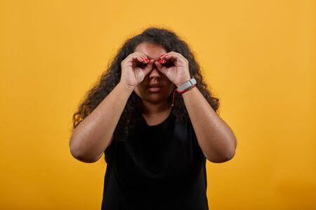 Afro-american young lady with overweight doing binocular, glasses on eyes, confused, over isolated...