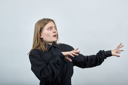 Disappointed young woman in fashion black shirt isolated on gray background in studio spreads hands...