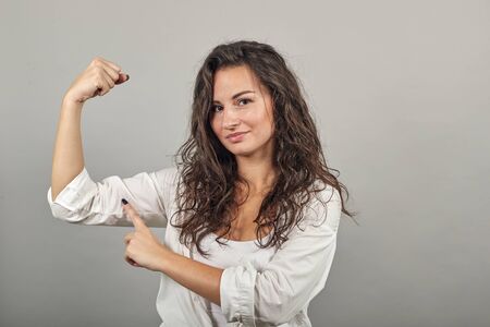 Feels proud have strength, shows great power, raises arms to show muscles confident in victory, looks strong and independent, flexing arm, facial expressions, feelings, attitude, life perceptionの写真素材