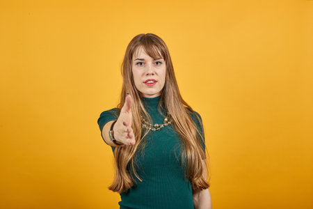 Human pulling hands to reach out each other. Almost reaching fingers outdoors. Individual interaction. Future concept. Studio shot. Hand stretch out for help. Young attractive woman, dressed greenの写真素材