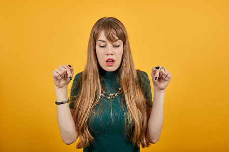Beautiful awesome young points with index fingers down. Shocked amazed posing isolated background, studio portrait. People sincere emotions lifestyle concept. Copy space. Looking. Positive expressionの写真素材
