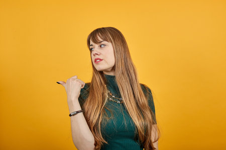 Pointing thumb over shoulder at blank space isolated. Astonished points with thumb aside. Look here. Studio photo portrait of satisfied sure, recommending cheerful nice human offering new solutionの写真素材