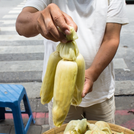 Photo of Hand hold boiled cornの写真素材