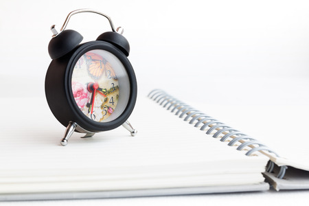 Alarm clock and notebook isolated on whiteの写真素材