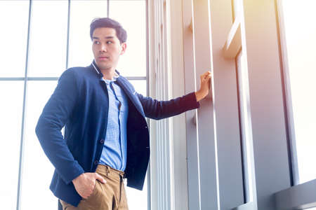 Handsome young businessman Asian caucasian wear a suit and long sleeve shirt in side, and standing smart poses in a modern office.の写真素材