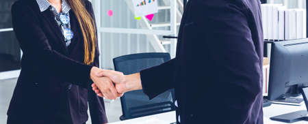 Young Asian Businesspersons are standing and handshake about a financial business concept to agree...