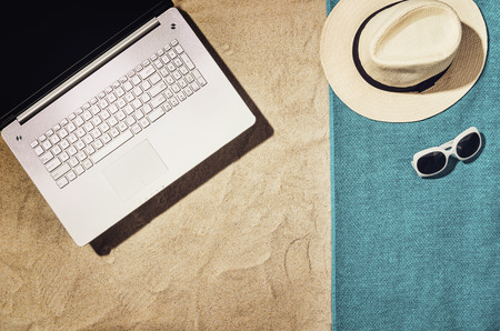 Top view of sandy beach with summer accessories and copy space around products. Blank mock up for...