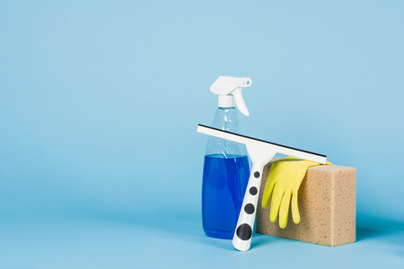 Cleaning concept - mixed detergents and cleaning accessories isolated on blue seamless background.