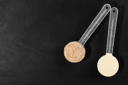 Product photograph of scoop of whey protein with visible texture on black chalkboard background. Image taken from above, top viewの写真素材