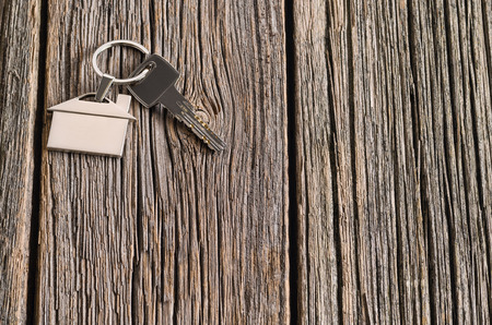Home, real-estate or property concept with silver keys with house symbol on old wooden floor background. Blank concept frame with copy spaceの写真素材