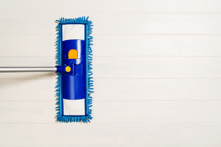 Cleaning floor with mop top view. Microfiber mop isolated on white wooden floor background. Home...
