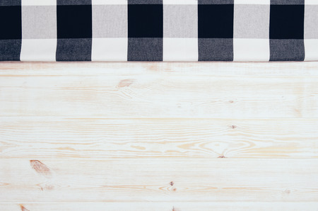 Top view of black checkered napkin or tablecloth on white wooden table with visible planks, texture and copy space for text.の写真素材