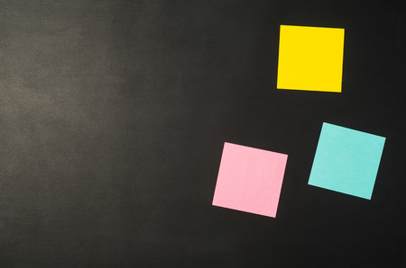 Sticky notes reminder on black chalkboard office table or desk seen from above. Top view product photograph. Concept image with blank copy spaceの写真素材