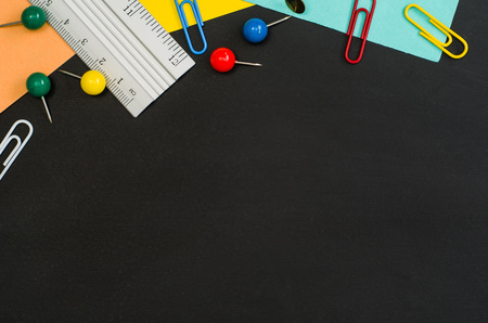 School supplies border on black chalkboard background. Top view product photograph with copy space for text or design. Back to school, education conceptの写真素材