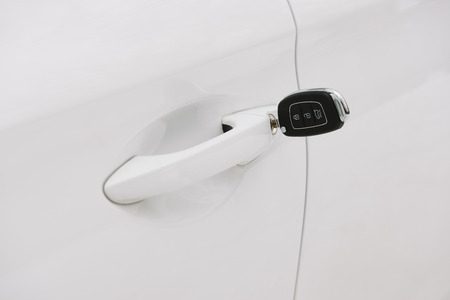 Car keys in white door lock closeup with copy space. Opening car door with keyの写真素材