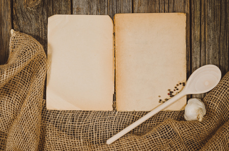 Vintage cookbook with cooking ingredients background. Top view photograph with kitchen utensils on vintage, natural, raw, wooden background with visible texture.の写真素材