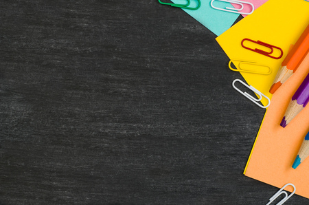 School supplies border on black chalkboard background. Top view product photograph with copy space for text or design. Back to school, education conceptの写真素材