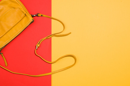 Womans accessories flat lay on colorful background. Top view. Red and yellow pastel colors with copy...