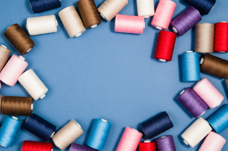 Top view of colorful thread spools over blue seamless background. Image taken from above.