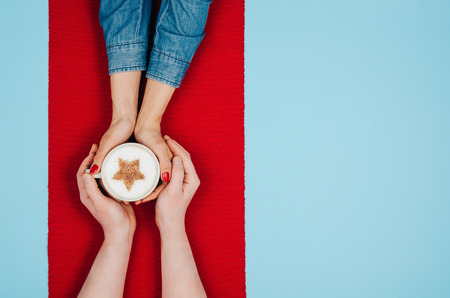 Couple in love holding hands with coffee on colorful table. Photograph taken from above, top view with copy spaceの写真素材